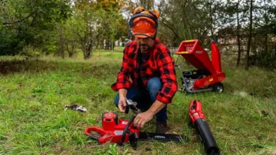 Muž s řetězovou pilou a sekací strojem pro likvidaci stromů.